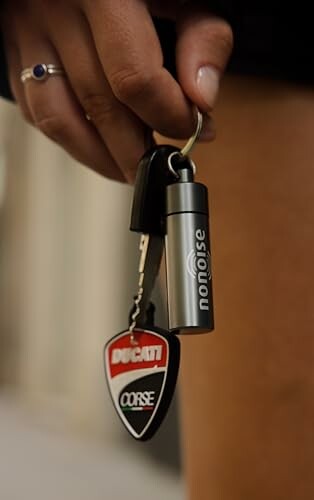 Hand mit Ducati-Schlüsselanhänger und NoNoise-Behälter