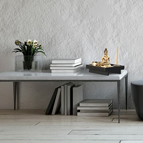 Minimalistische Tischdekoration mit Buddha-Statue und Pflanzen.