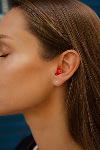 Nahaufnahme einer Frau mit roten Ohrstöpseln.